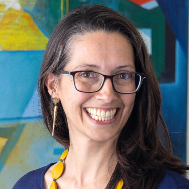 Laura Mary Cincotta - The Designer's Translator. Headshot with painting by Martha D. Gerardo in the background. Credit: Jennifer Skinner